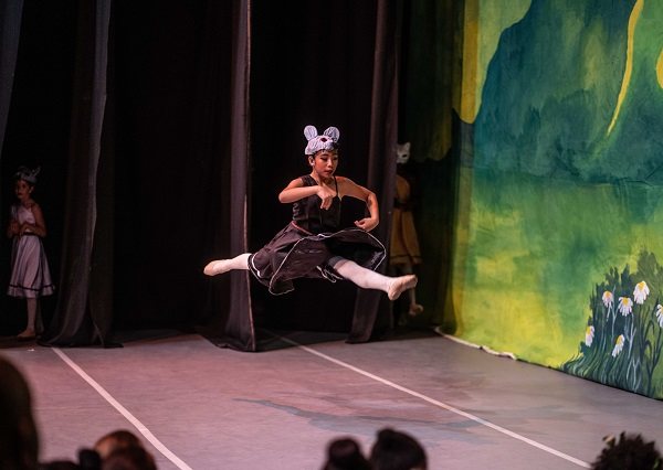 A dancer leaps mid-air as the field mouse